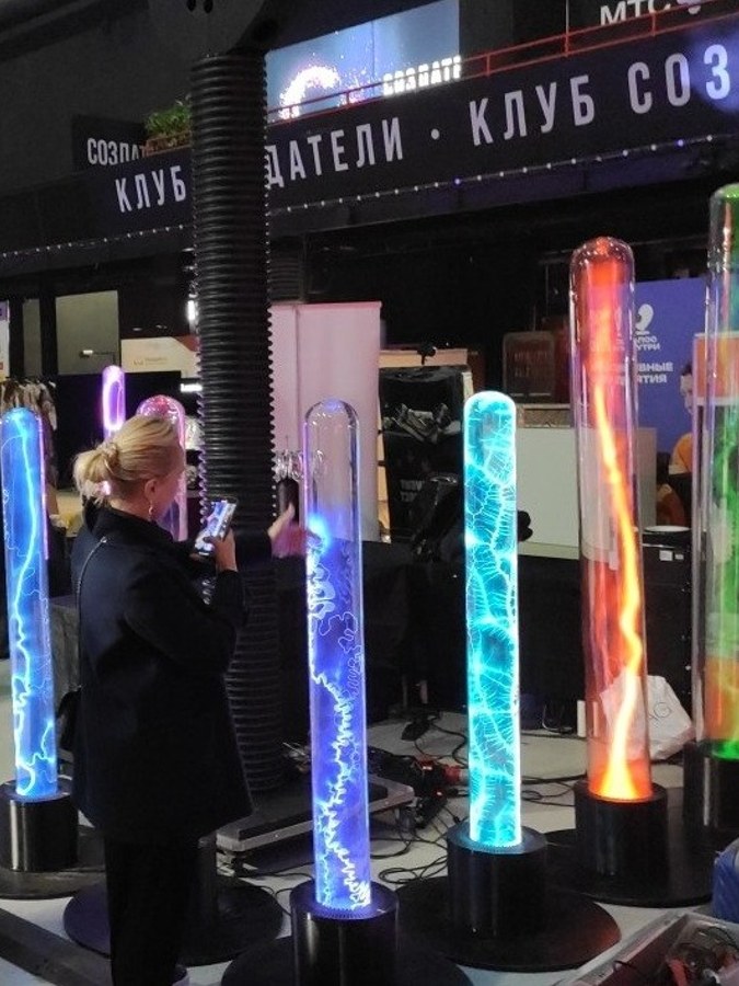 A visitor filming plasma tubes on her phone at an exhibition