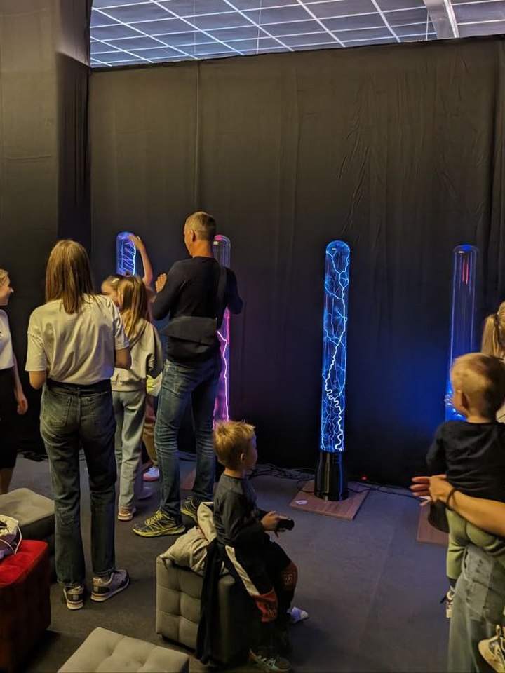 Adults and children touching plasma columns at an event