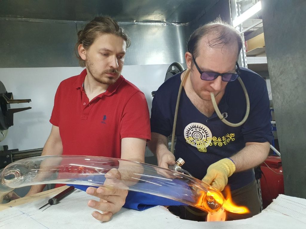 Glassblowers bending a section of the torus